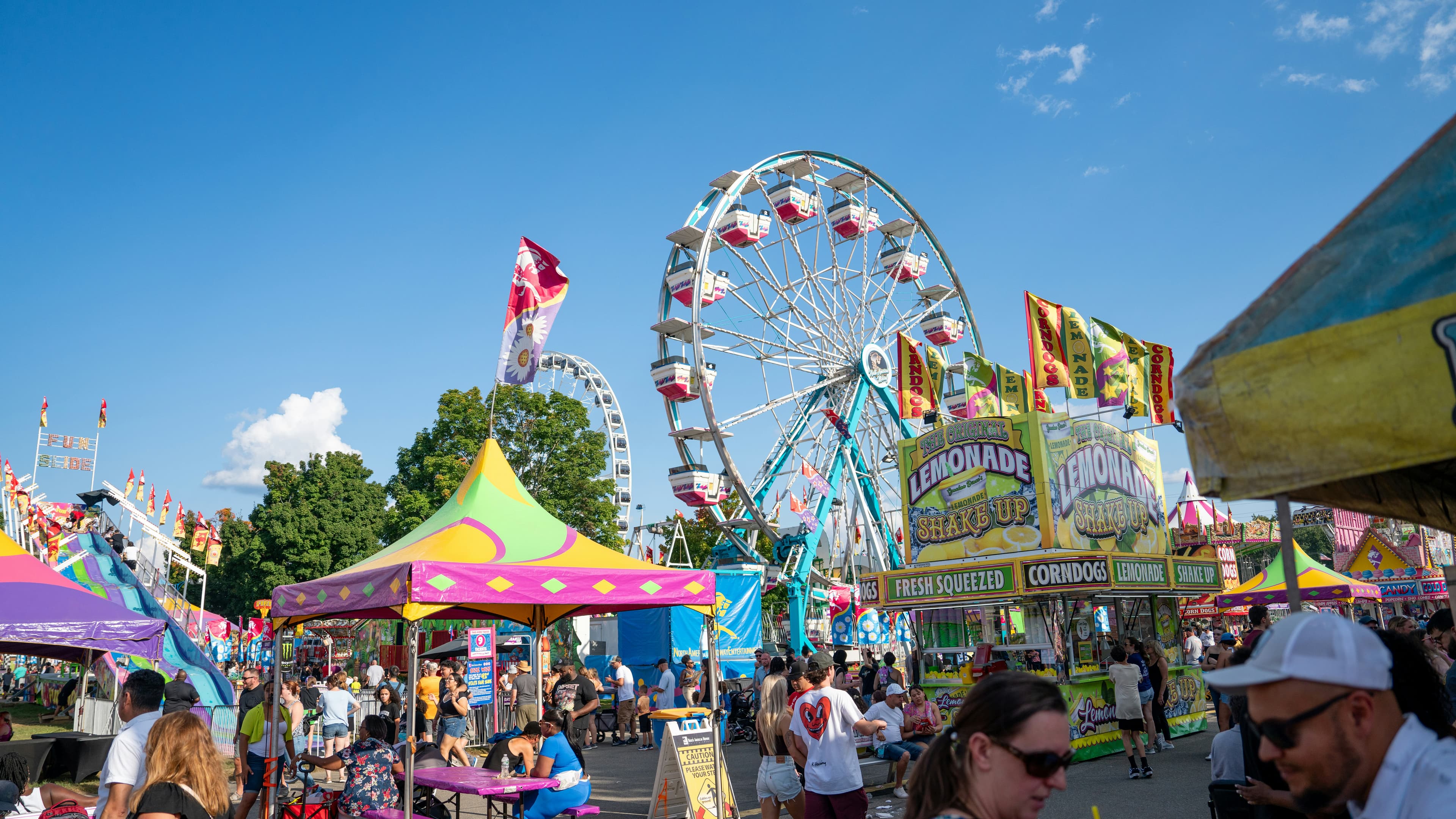 County fair midway at dusk with Ferris wheel lit up