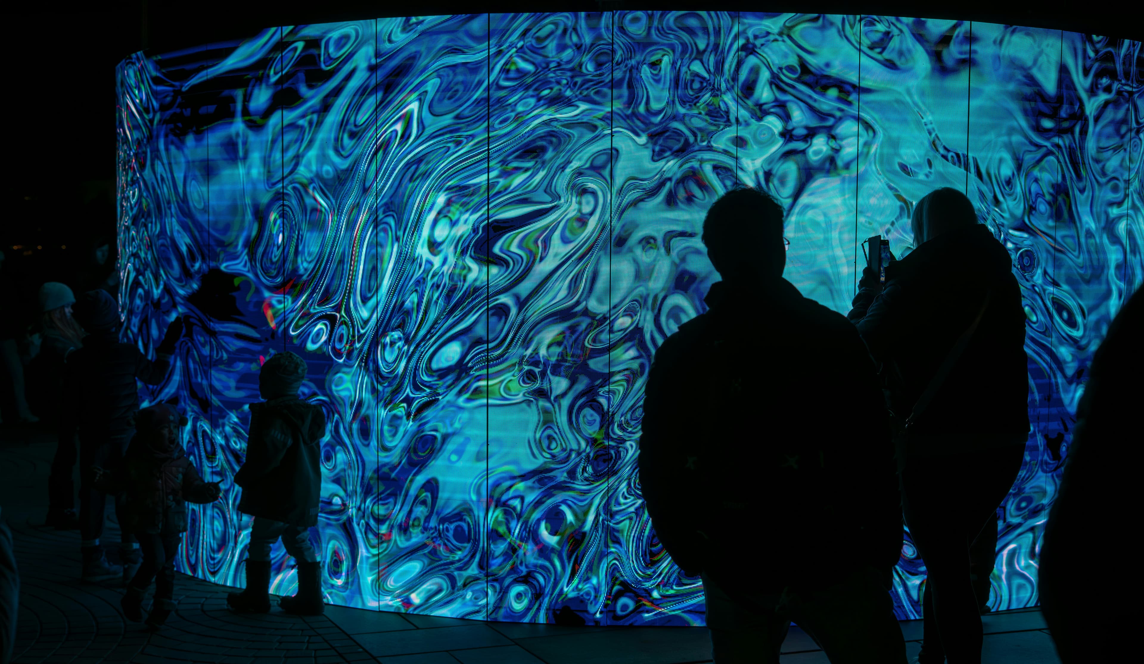 Visitors exploring a colorful immersive light installation