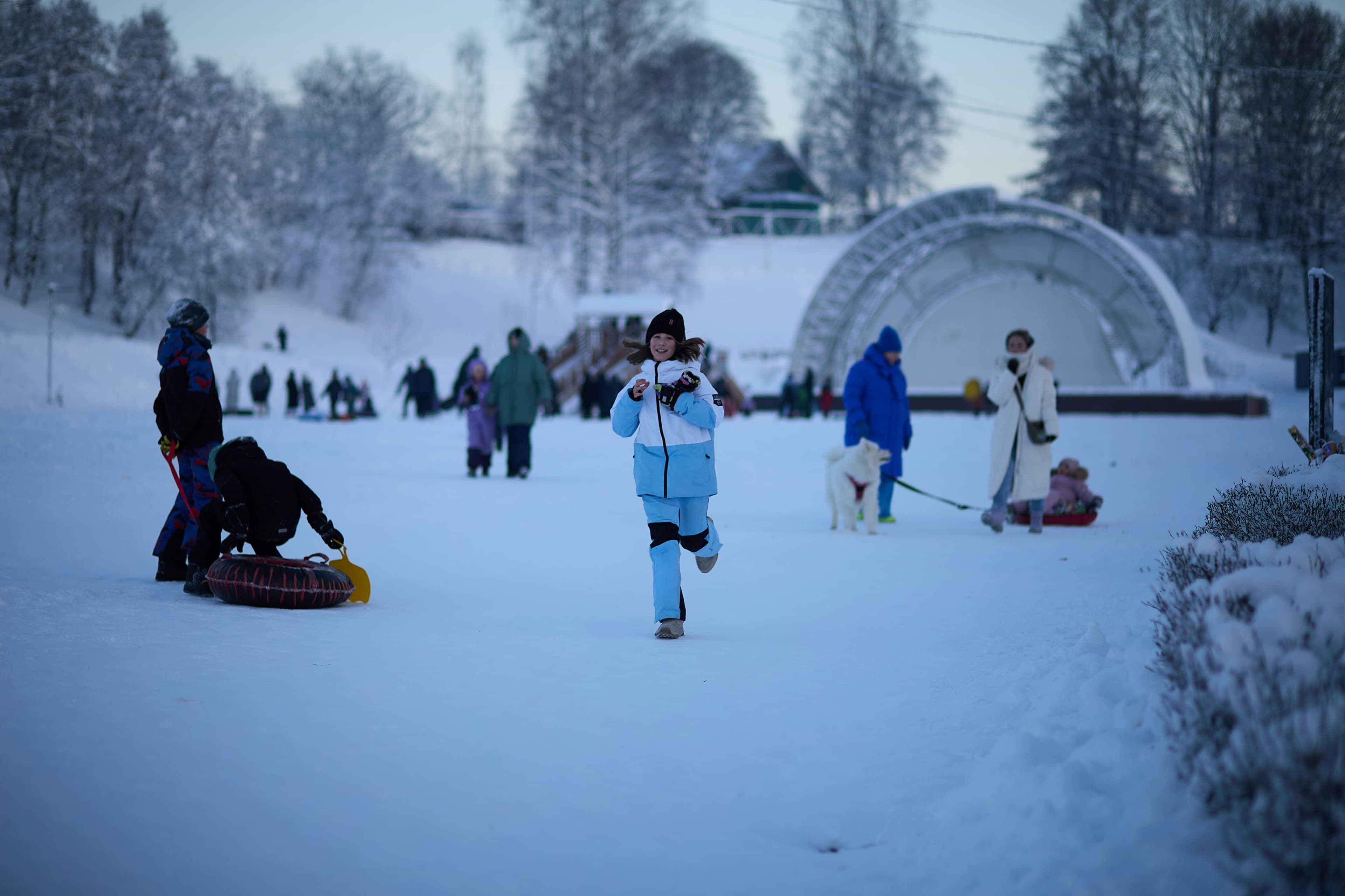 Snow tubing hill with families in winter gear